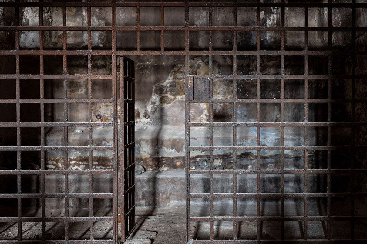 Prison cell with bars and peeling paint on the walls